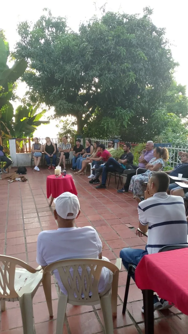 Familias y residentes reunidos bajo los árboles en la terraza de la finca